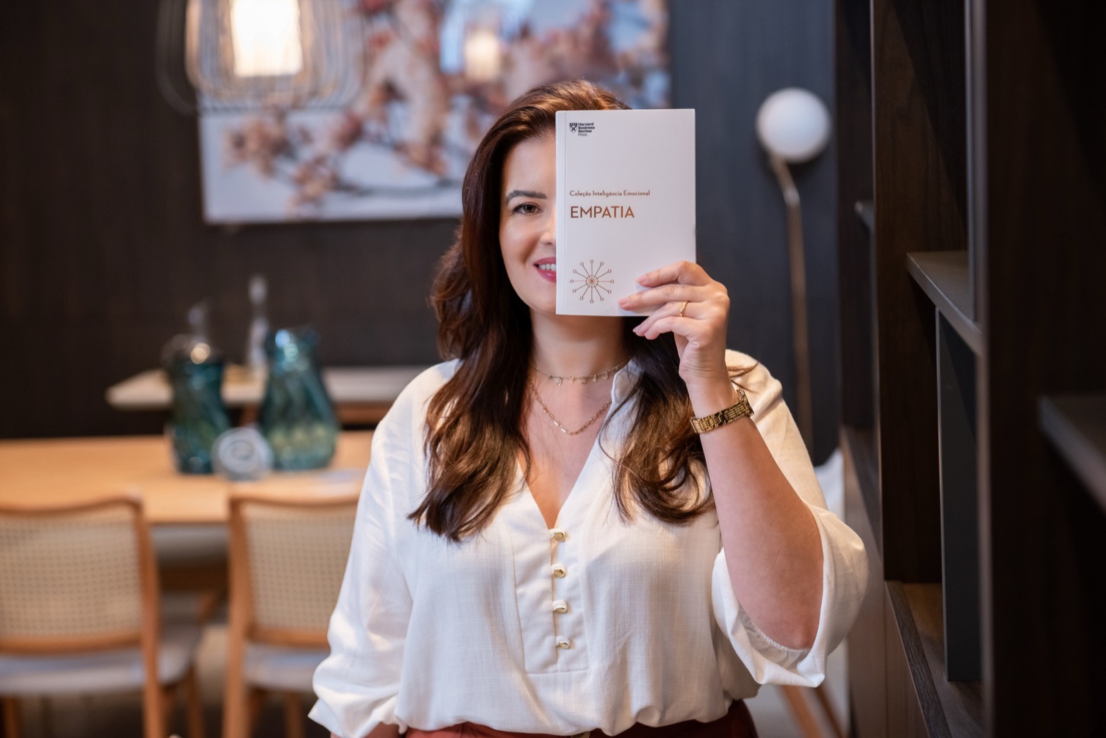 Retrato de uma mulher sorrindo e segurando um livro sobre empatia